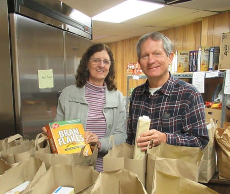 Dave and Deb are filling grocery bags to give to clients
