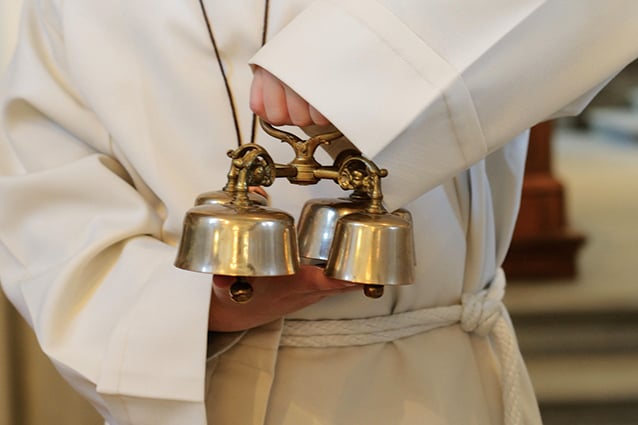 Altar server holding bells.