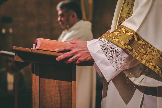 Priest holding Bible open.