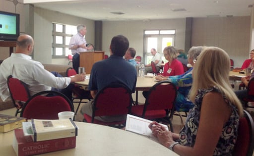 image of adult bible study group at tables listening to speaker