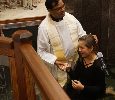 image of Father Albeen in baptismal font with catechumen